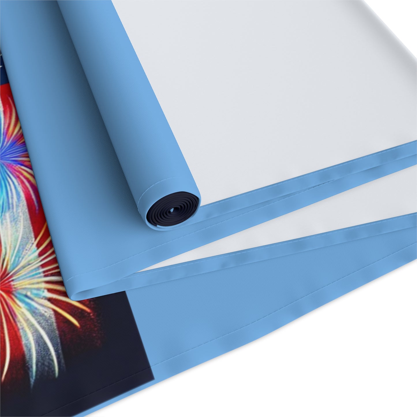 Close-up image of a rolled Atlanta-themed table runner showing blue borders, clean stitching, and durable fabric with a glimpse of a vibrant fireworks design, highlighting quality craftsmanship and finish.