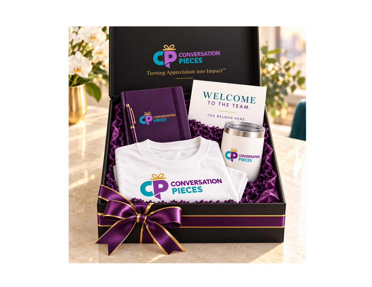 Conversation Pieces Basic welcome kit with a folded white branded T-shirt, purple notebook and pen, white tumbler, and welcome card in a black gift box with purple-and-gold ribbon.