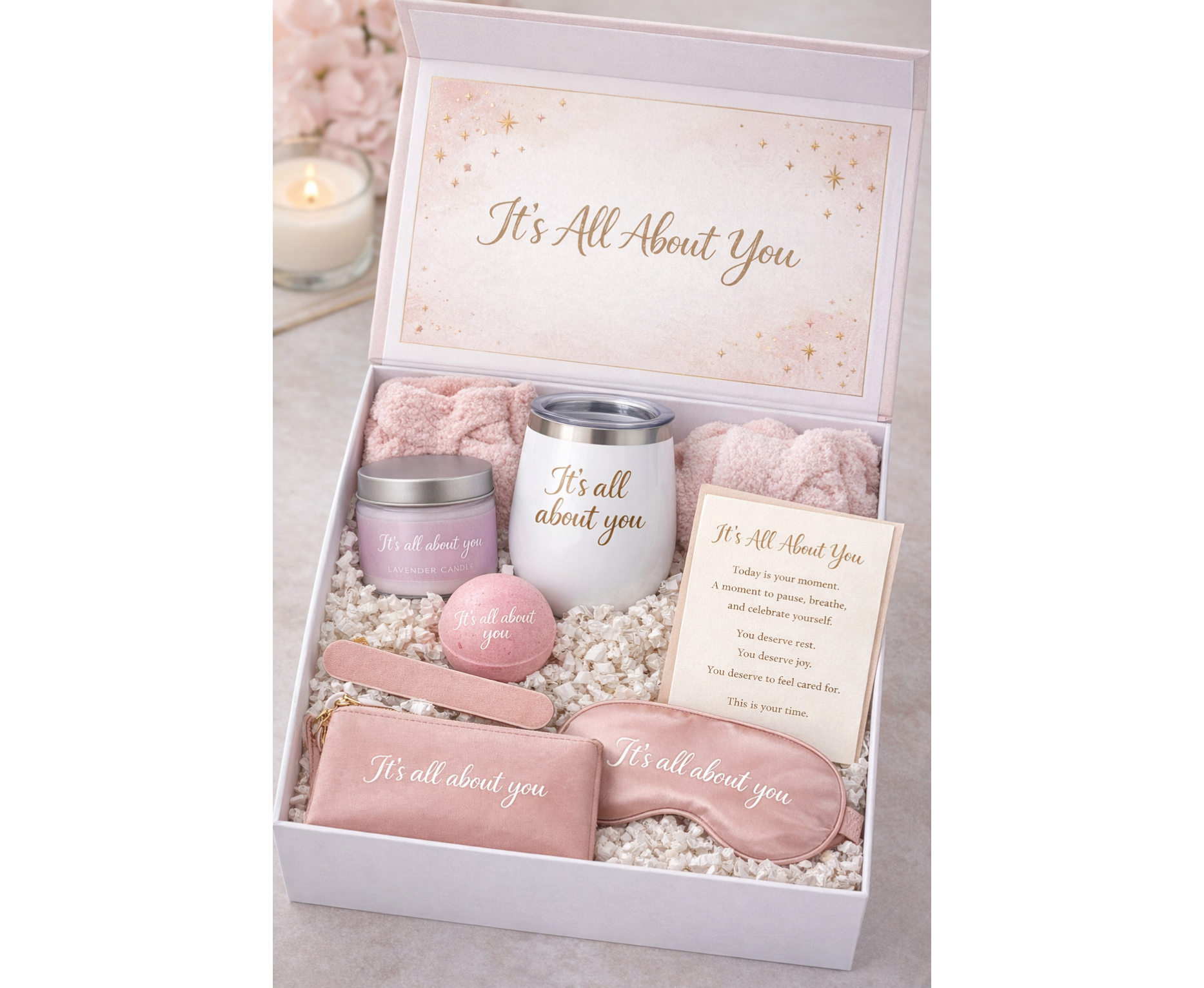 Gift set with pink items including a candle, eye mask, and card in a box labeled 'It's All About You'.