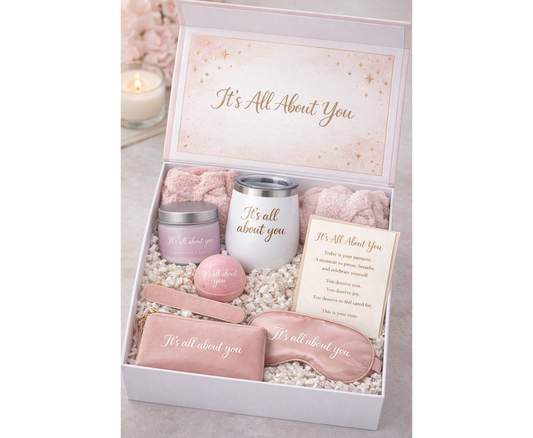 Gift set with pink items including a candle, eye mask, and card in a box labeled 'It's All About You'.