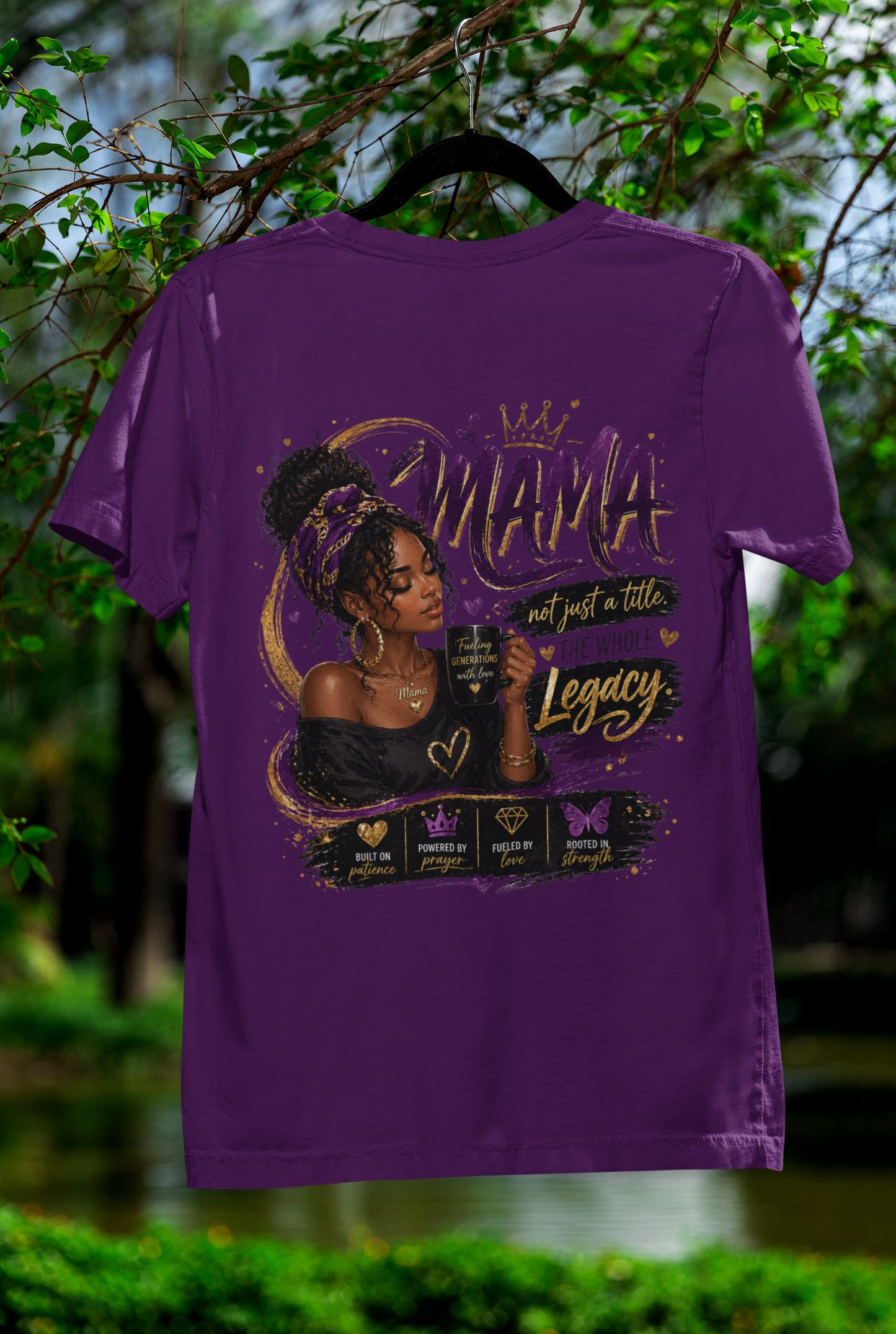 Purple t-shirt with a graphic design of a woman and text, hanging outdoors with greenery in the background.