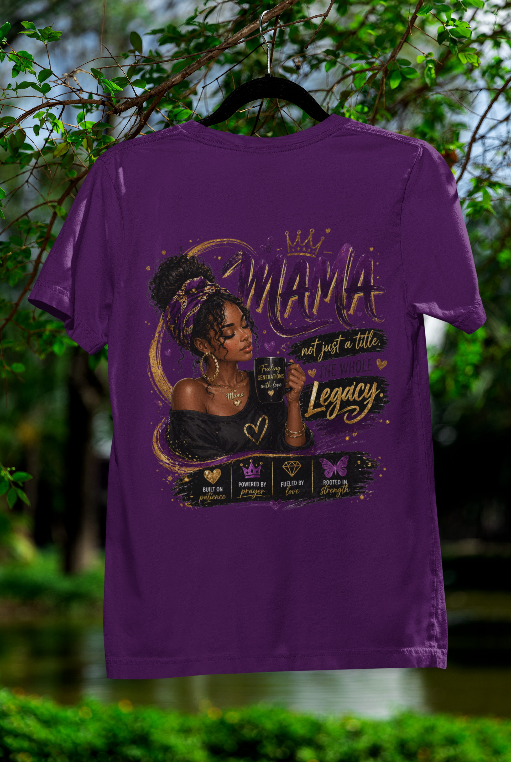 Purple t-shirt with a graphic design of a woman and text, hanging outdoors with greenery in the background.
