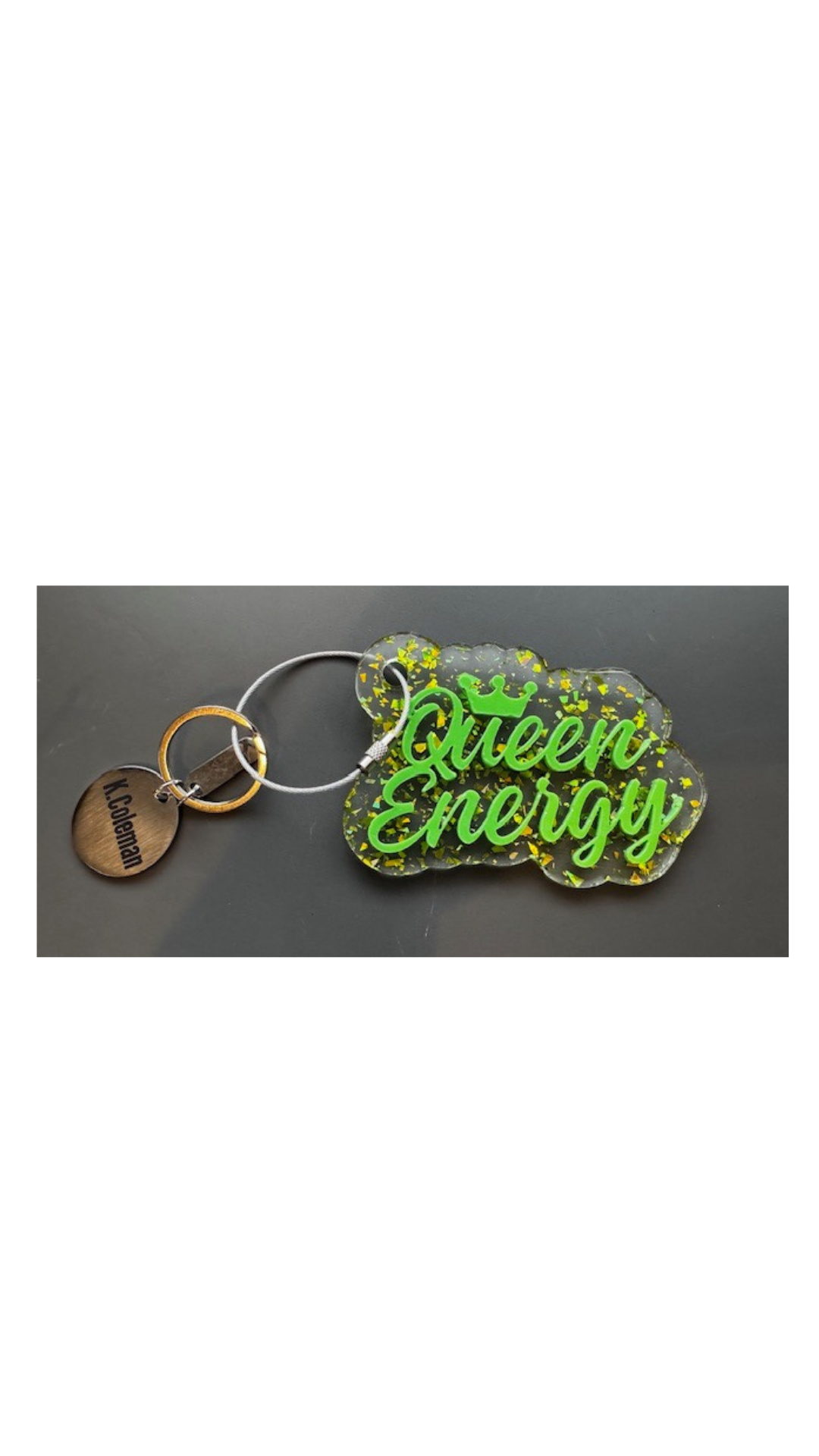A green acrylic keychain with the text 'Queen Energy' written on it, displayed on a grey background.