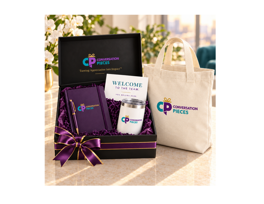 Conversation Pieces welcome kit with notebook, pen, white tumbler, and welcome card in a black box with purple-and-gold ribbon, beside a linen-colored branded tote.