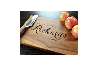 Wooden cutting board with engraved name 'Richard' and knife on a dark surface with apples.